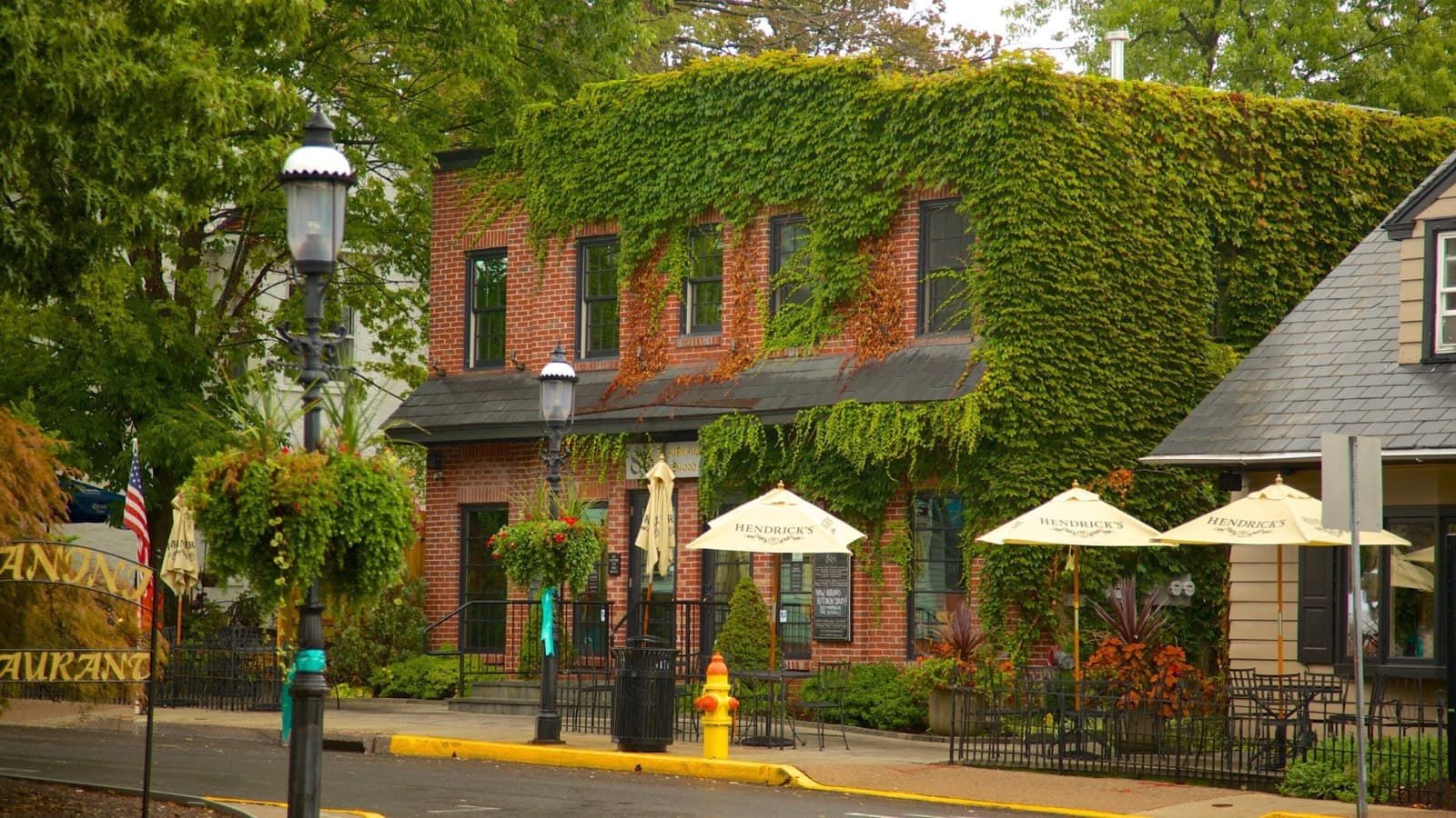An ivy-covered brick building with sidewalk cafe umbrellas on West State Street in downtown Doylestown